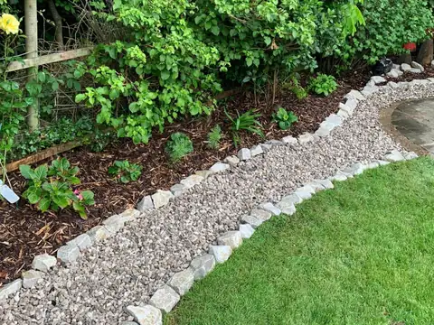 Border planted with shrubs beside a gravel strip and lawn